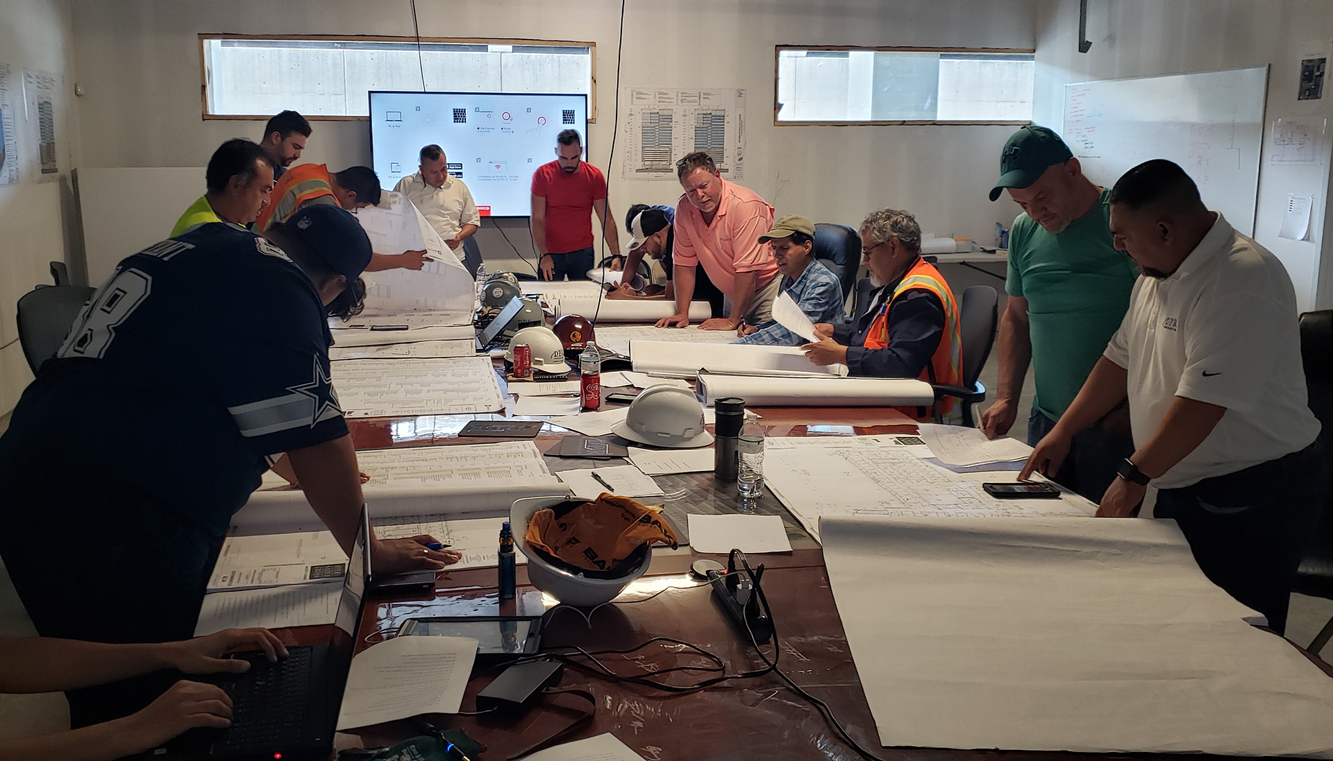 Participants in DPR’s apprenticeship program around a table reviewing construction drawings.
