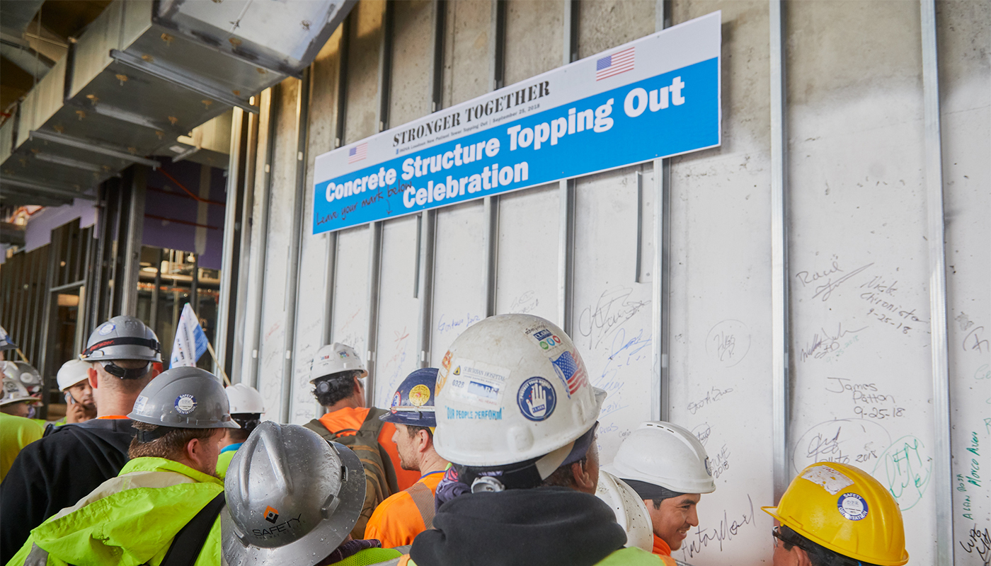 Subcontractors sign the wall, leaving their mark on the project during the concrete topping out celebration.