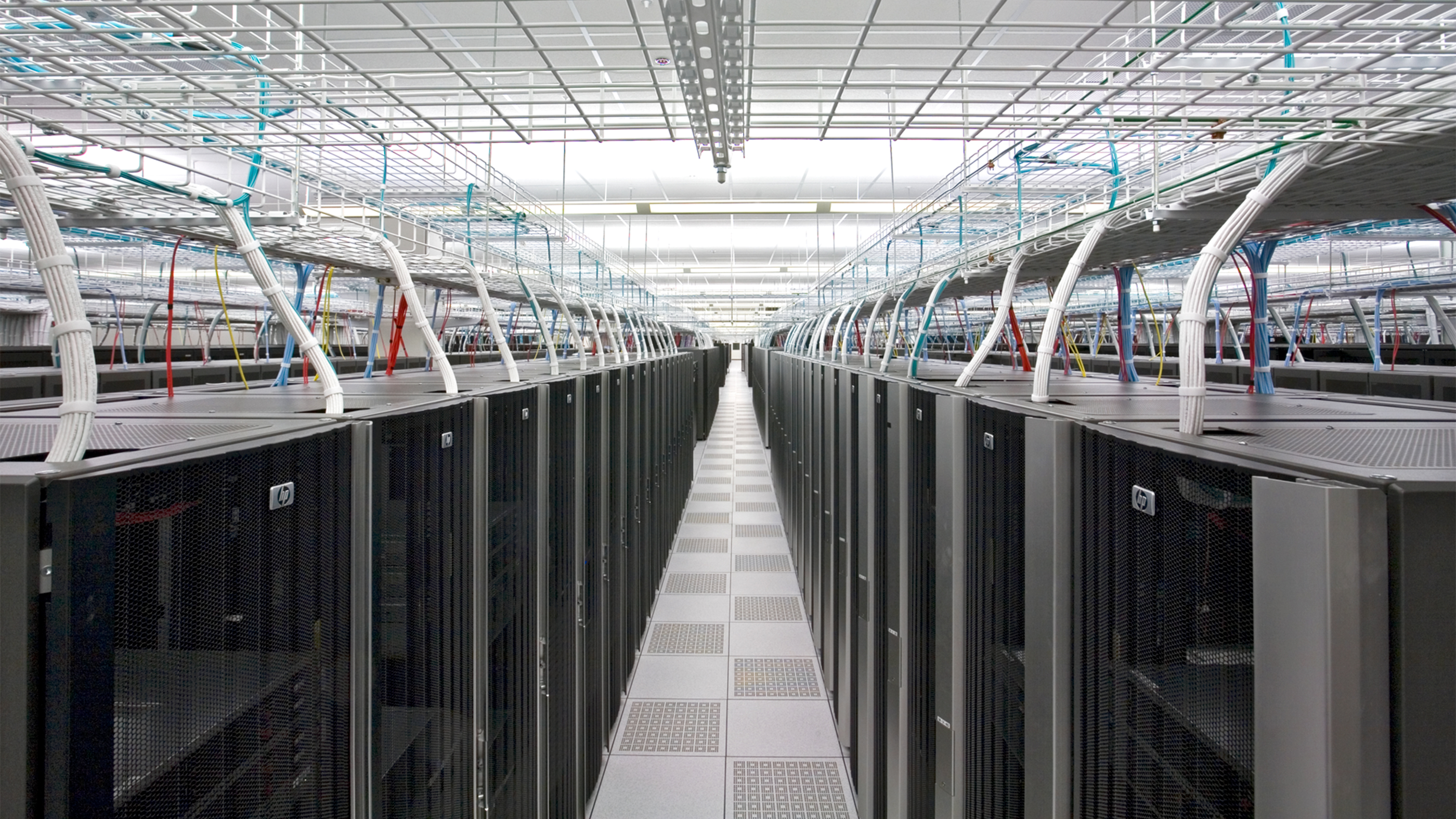 View down a server aisle with organized wiring above the rows.